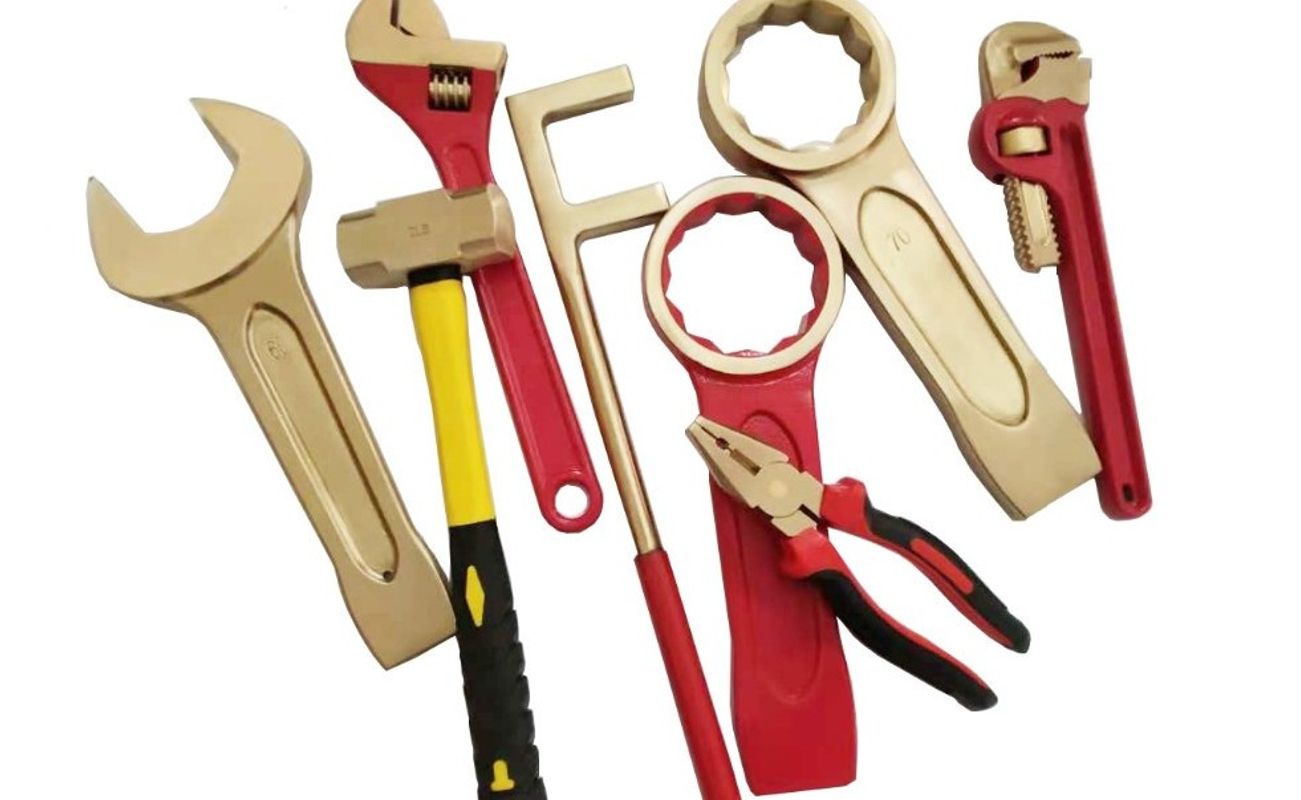 Eine Sammlung von goldfarbenen und roten Werkzeugen, darunter ein Schraubenschlüssel, eine Zange, ein Hammer und ein Rohrschlüssel.